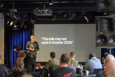 Lauri Jutila on stage with a slide reading 'This talk may not exist in October 2026'